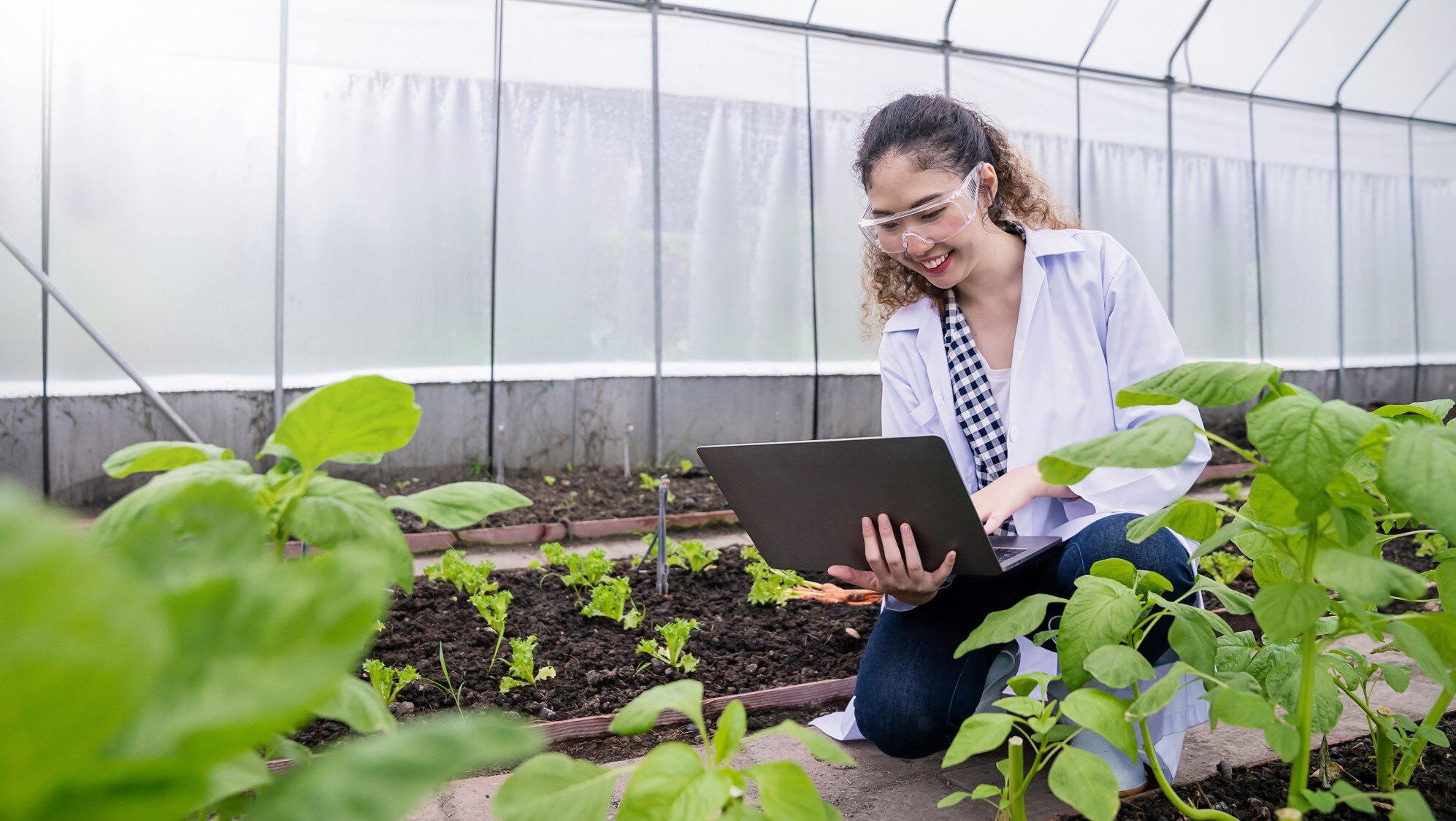 Greenhouse worker smiling on laptop